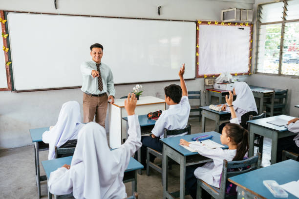 primary school and pupils in classroom. elementary students doing exam and being supervised by male teacher - 教育 個(gè)照片及圖片檔