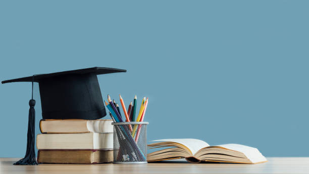 graduation day.a mortarboard and graduation scroll on stack of books with pencils color in a pencil case on blue background.education learning concept. - 教育 個(gè)照片及圖片檔